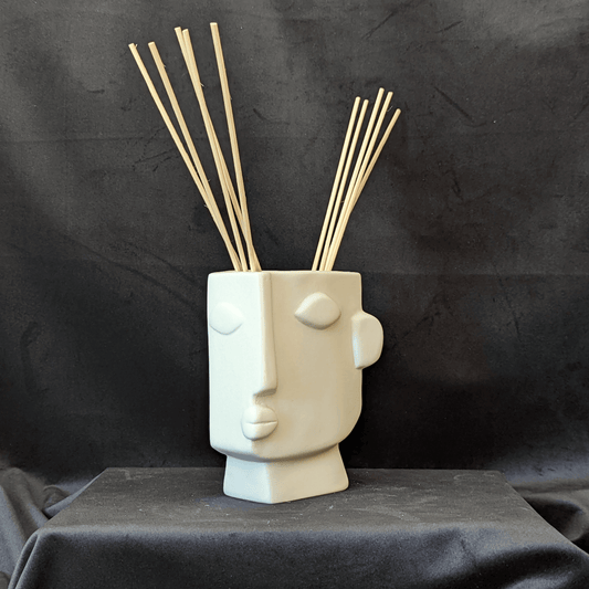 Cream vase with an artistic expression of a human face. It is square in shape with the face on a 3/4 angle.